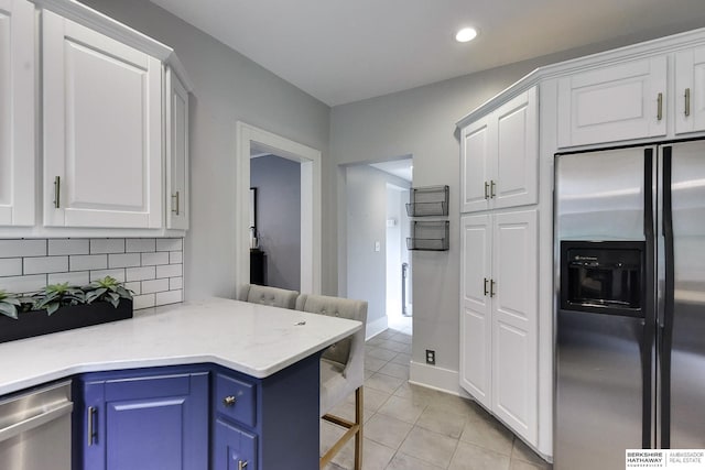 kitchen with appliances with stainless steel finishes, a breakfast bar, white cabinets, and blue cabinets