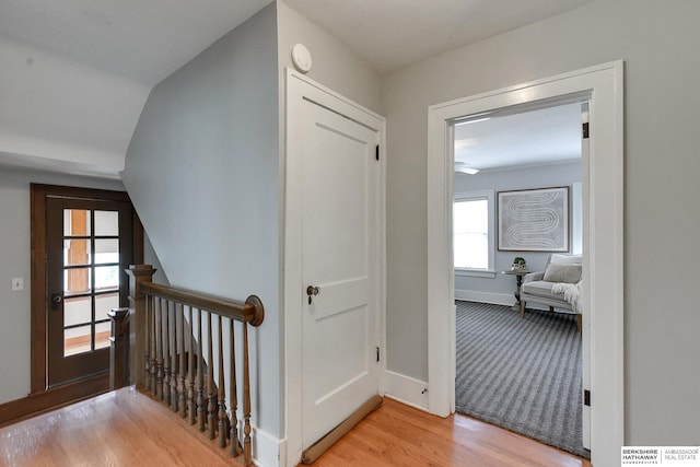 corridor with light hardwood / wood-style floors and vaulted ceiling