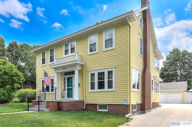 colonial house with a front lawn, a garage, and an outdoor structure