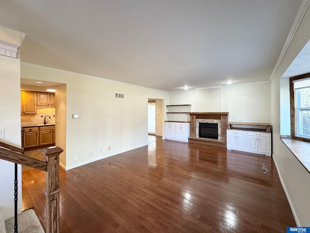 unfurnished living room with sink, dark hardwood / wood-style flooring, and ornamental molding