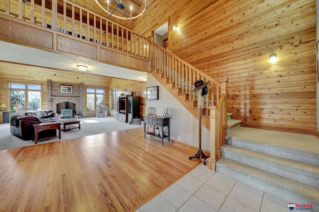 staircase featuring a towering ceiling, tile patterned flooring, a brick fireplace, and a chandelier