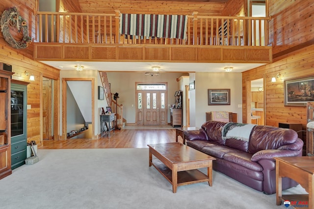 carpeted living room featuring a towering ceiling and wood walls