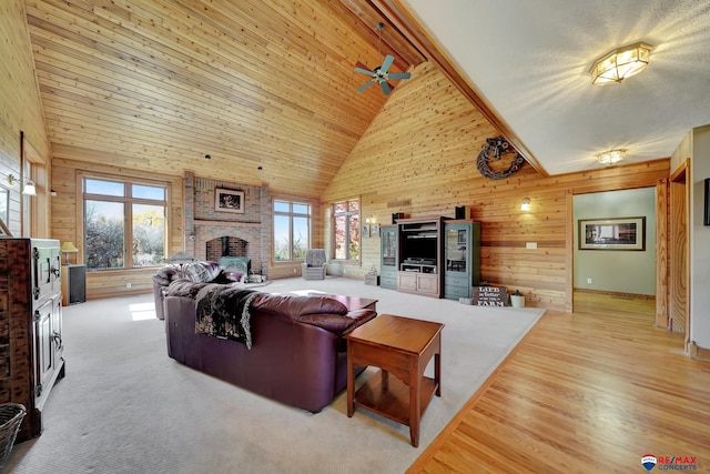 living room with a fireplace, high vaulted ceiling, ceiling fan, and wood ceiling