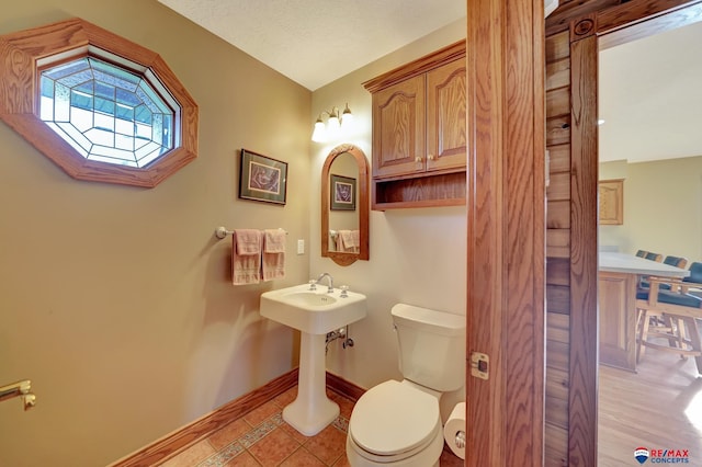 bathroom featuring a textured ceiling, tile patterned floors, and toilet