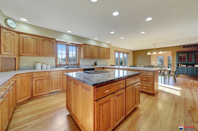 kitchen featuring decorative light fixtures, plenty of natural light, light hardwood / wood-style flooring, and a center island