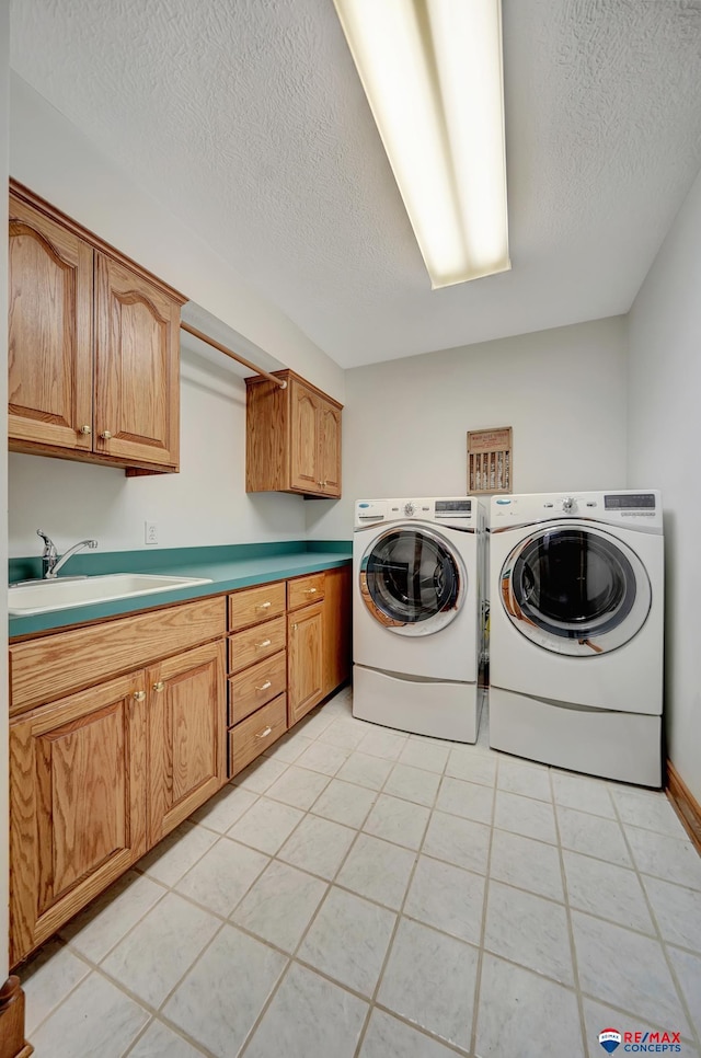 washroom with sink, cabinets, washer and clothes dryer, and a textured ceiling