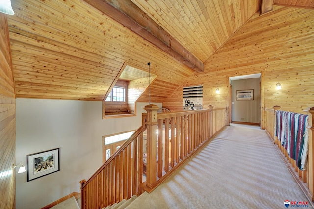 hallway with beam ceiling, wooden walls, wooden ceiling, and light carpet