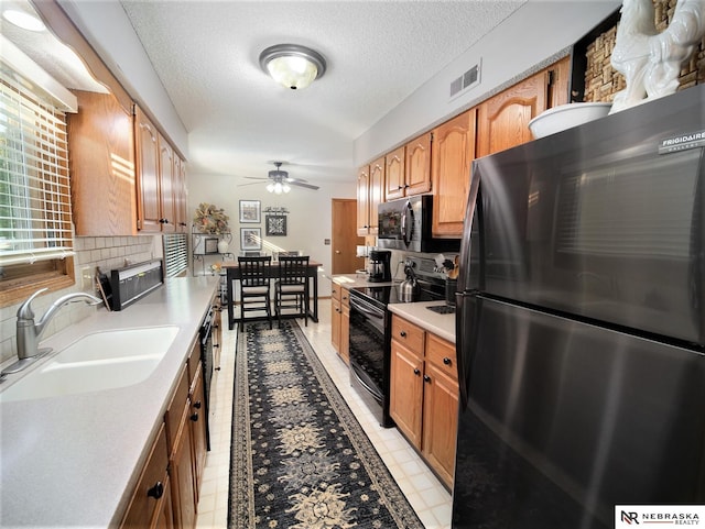 kitchen featuring sink, electric stove, a textured ceiling, and stainless steel fridge