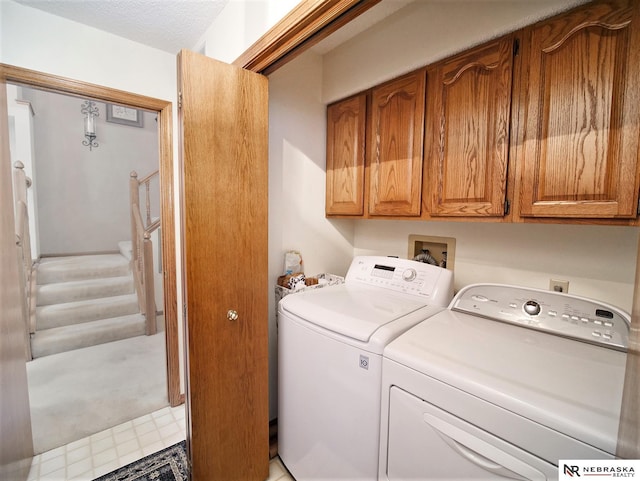 laundry room with washer and clothes dryer, a textured ceiling, and cabinets