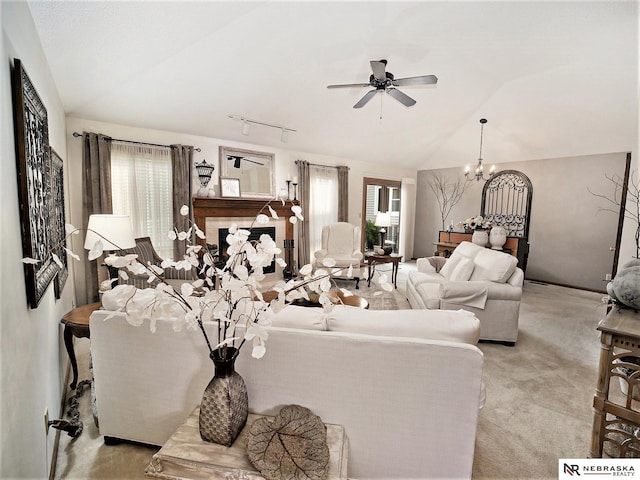 living room featuring ceiling fan with notable chandelier, lofted ceiling, rail lighting, and light carpet