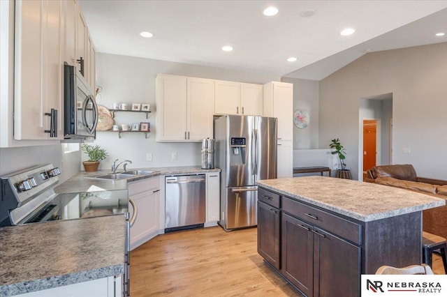 kitchen featuring vaulted ceiling, a center island, white cabinets, appliances with stainless steel finishes, and sink