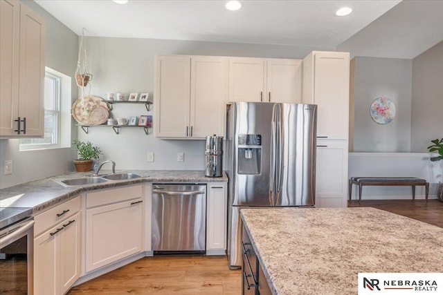 kitchen with stainless steel appliances, white cabinets, sink, and light hardwood / wood-style flooring