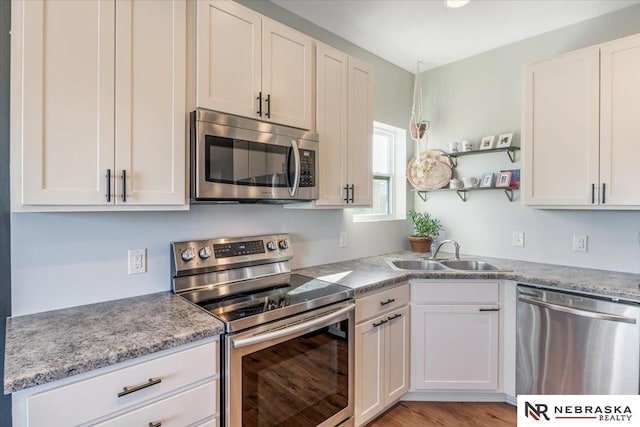 kitchen with stainless steel appliances, white cabinetry, light hardwood / wood-style flooring, and sink