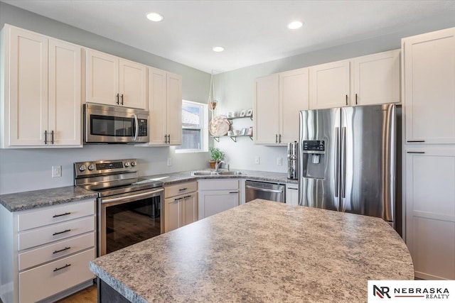 kitchen with stainless steel appliances, a kitchen island, white cabinets, and sink