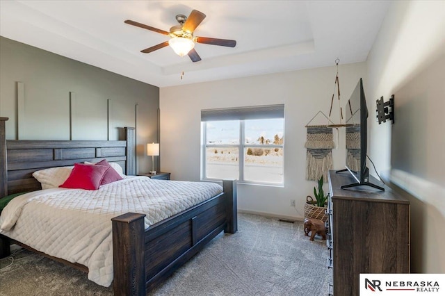 bedroom with light colored carpet, ceiling fan, and a tray ceiling