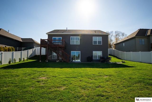 rear view of house featuring a wooden deck and a lawn