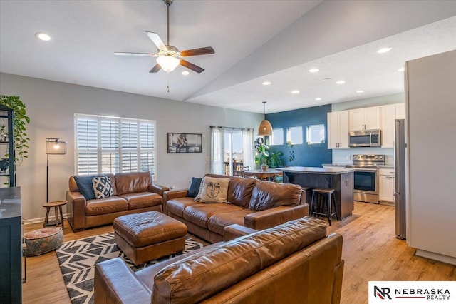 living room with lofted ceiling, light hardwood / wood-style floors, and a wealth of natural light