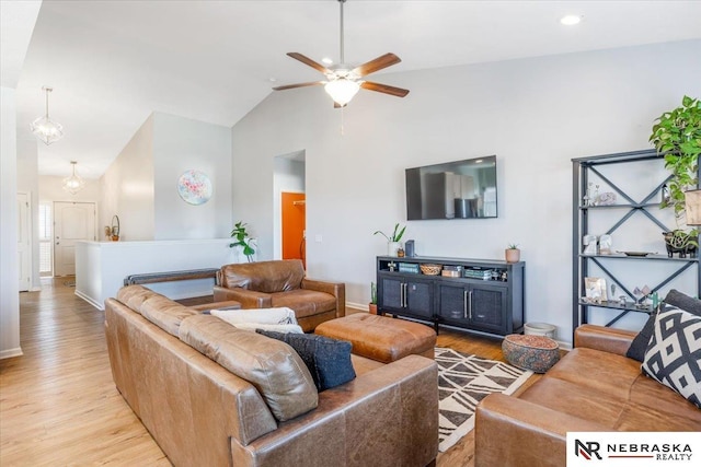 living room featuring light hardwood / wood-style floors, vaulted ceiling, and ceiling fan with notable chandelier