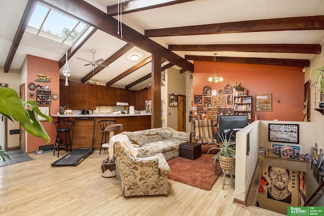 living room with beamed ceiling, indoor bar, light wood-type flooring, and ceiling fan with notable chandelier