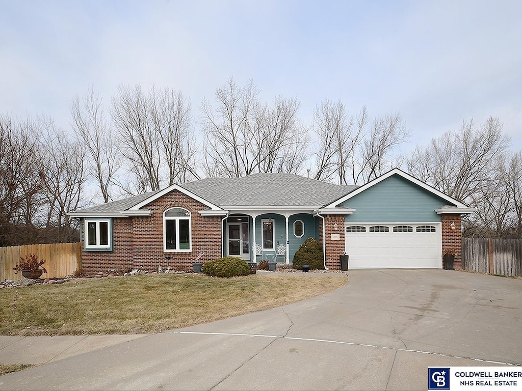 ranch-style house with a garage, a porch, and a front lawn