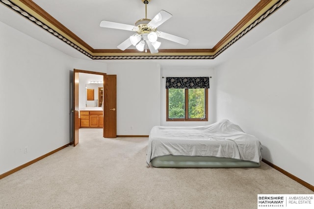 unfurnished bedroom with a raised ceiling, light carpet, crown molding, ceiling fan, and ensuite bathroom