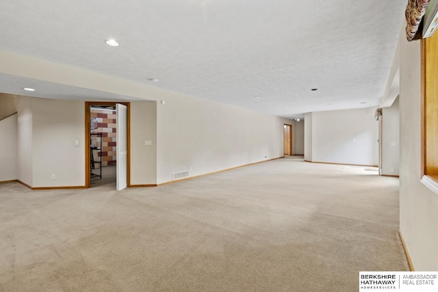 unfurnished room featuring a textured ceiling and light colored carpet