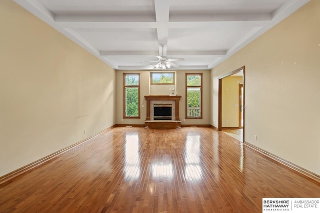 unfurnished living room featuring a fireplace, beamed ceiling, ceiling fan, light hardwood / wood-style floors, and coffered ceiling