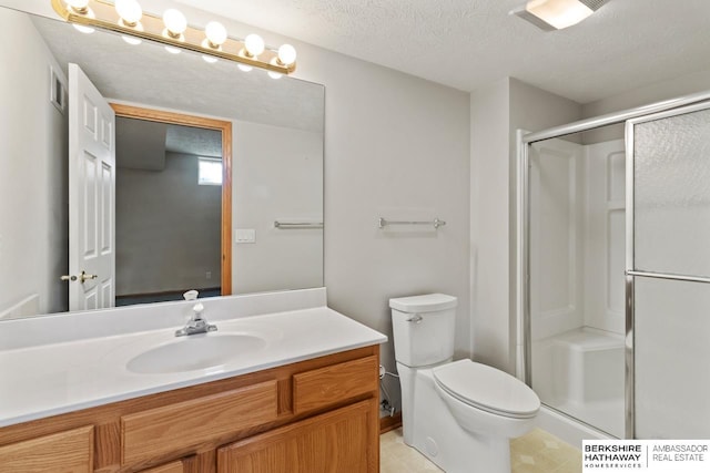 bathroom with toilet, vanity, a textured ceiling, and a shower with shower door