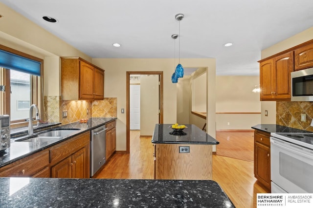 kitchen with stainless steel appliances, sink, light wood-type flooring, hanging light fixtures, and a kitchen island