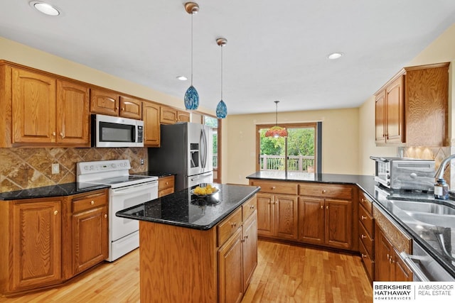 kitchen with decorative light fixtures, tasteful backsplash, kitchen peninsula, a kitchen island, and appliances with stainless steel finishes