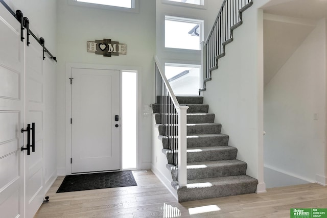 entryway featuring light hardwood / wood-style floors, a barn door, and a high ceiling