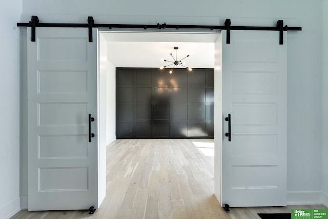 doorway with a chandelier, a barn door, and light hardwood / wood-style flooring