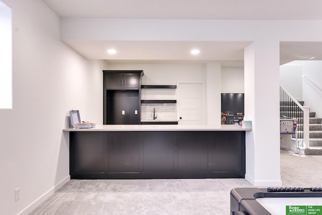 kitchen featuring sink, a kitchen bar, kitchen peninsula, and light colored carpet