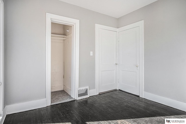 unfurnished bedroom with dark wood-type flooring and a closet