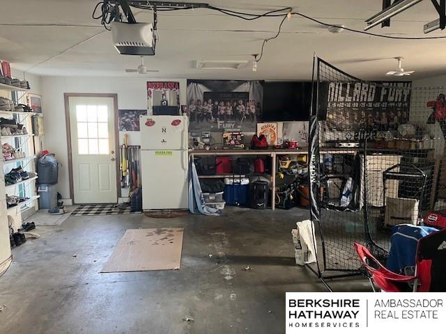 garage featuring a workshop area, white fridge, and a garage door opener