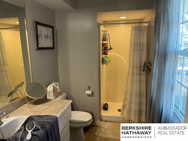 bathroom with toilet, a shower with shower curtain, a wealth of natural light, and vanity