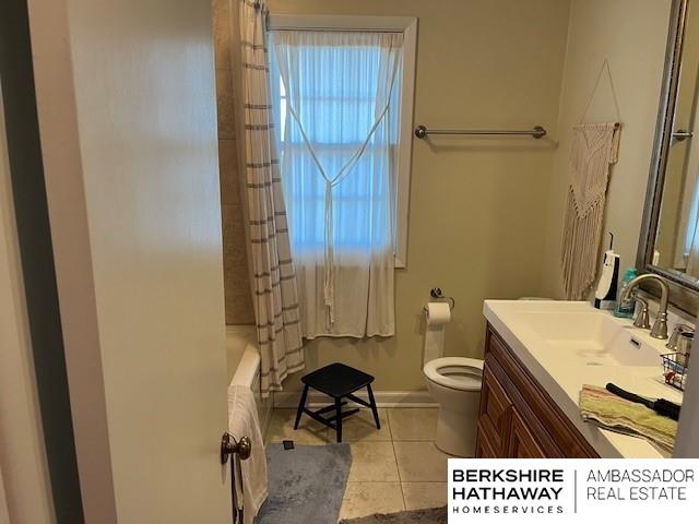 full bathroom with toilet, vanity, tile patterned flooring, and shower / bath combo with shower curtain