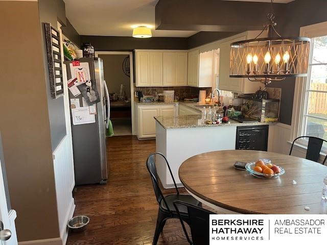 kitchen with a notable chandelier, sink, white cabinetry, hanging light fixtures, and stainless steel fridge