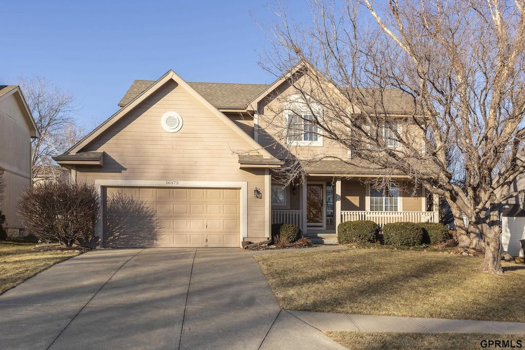 view of front facade with a porch, a front yard, and a garage