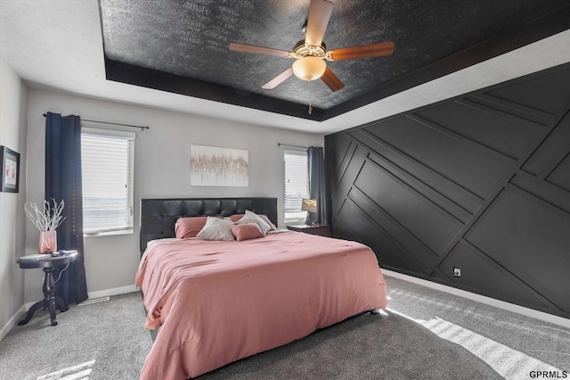 carpeted bedroom featuring a raised ceiling and ceiling fan