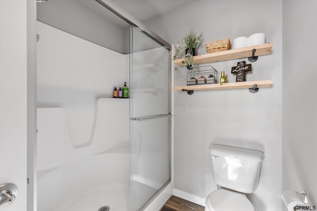 bathroom with wood-type flooring, walk in shower, and toilet