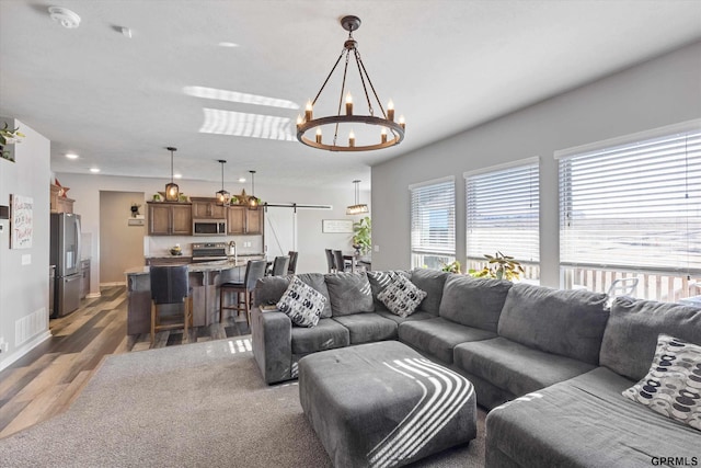 living room with an inviting chandelier, a barn door, and dark hardwood / wood-style floors