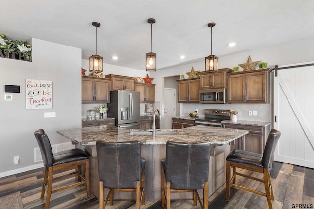 kitchen with stainless steel appliances, a kitchen bar, a barn door, and hanging light fixtures