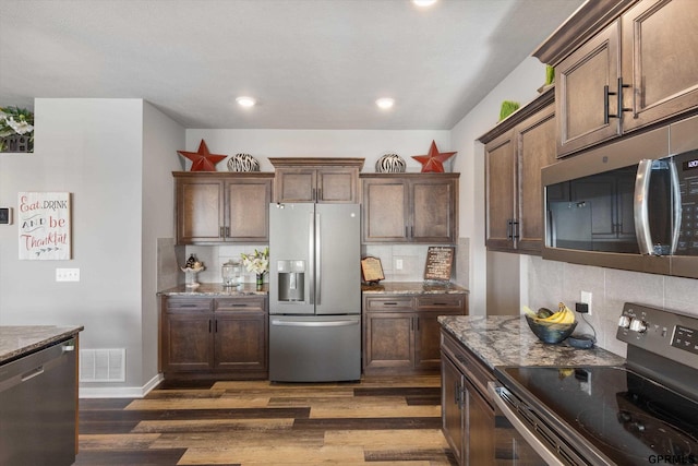 kitchen with stainless steel appliances, dark hardwood / wood-style flooring, light stone counters, dark brown cabinets, and tasteful backsplash