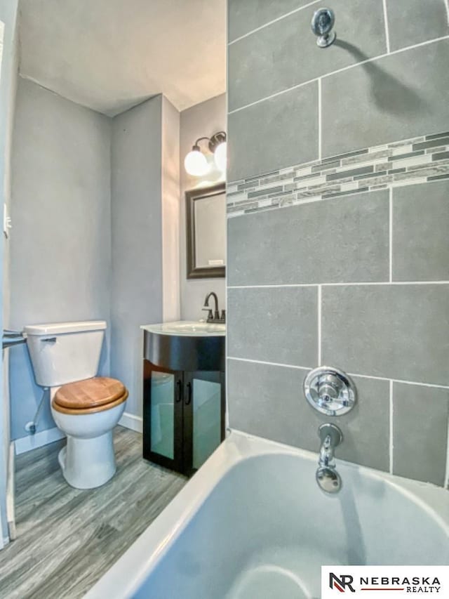 bathroom with toilet, hardwood / wood-style floors, and tiled shower / bath combo