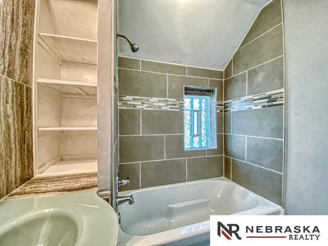 bathroom with tiled shower / bath combo and vaulted ceiling