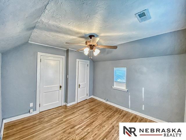 bonus room with ceiling fan, lofted ceiling, a textured ceiling, and wood-type flooring