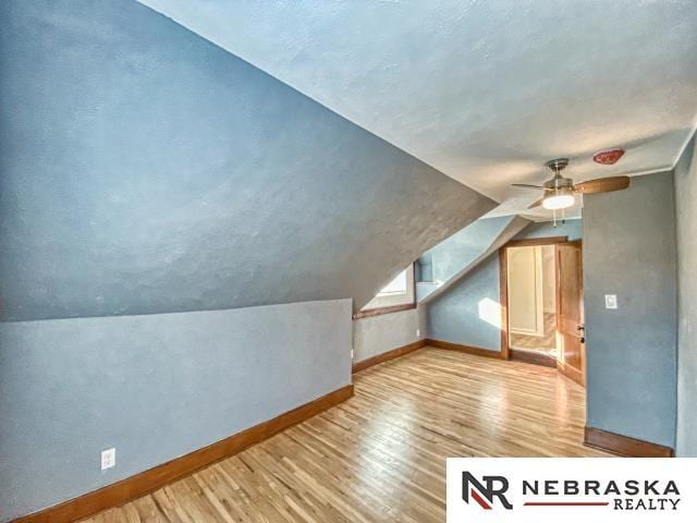 additional living space featuring ceiling fan, light wood-type flooring, and vaulted ceiling