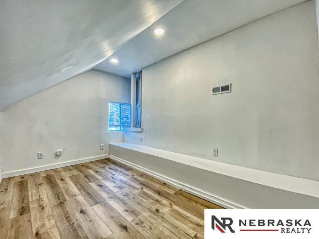 additional living space featuring lofted ceiling and light hardwood / wood-style flooring