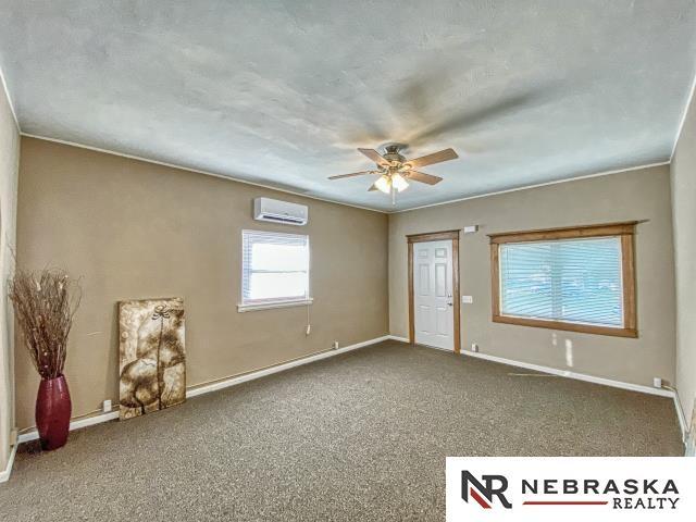 carpeted spare room with ceiling fan and a wall mounted AC